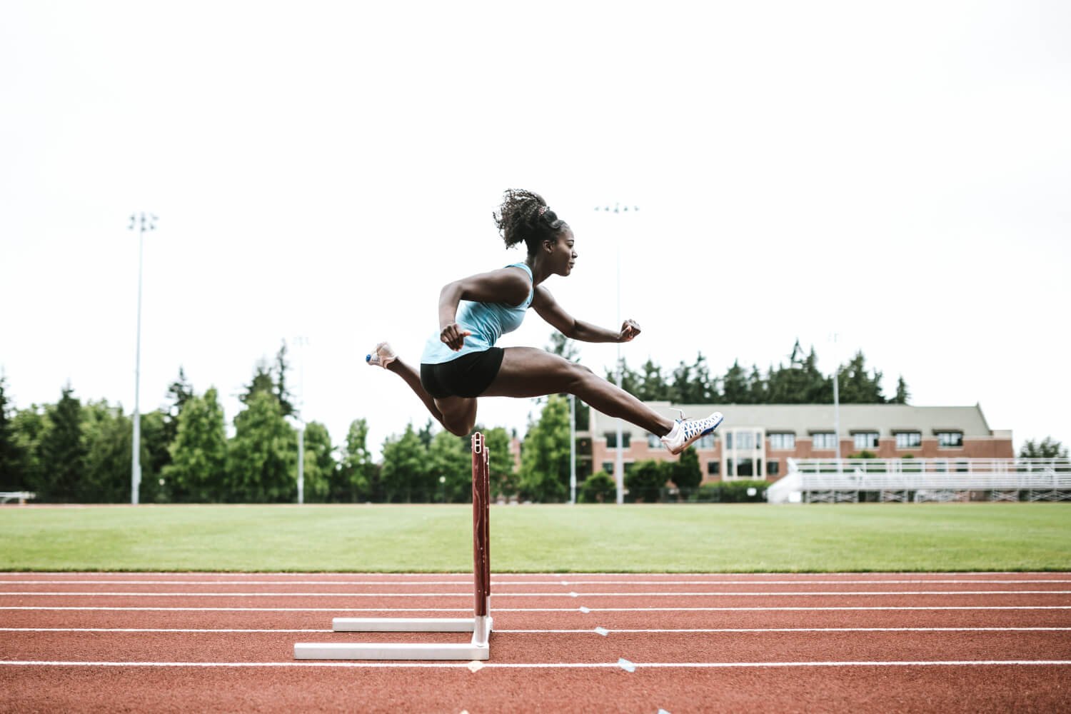 woman doing a hurdle on a track