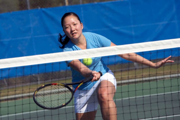 Female athlete playing tennis about to hit a shot at the net