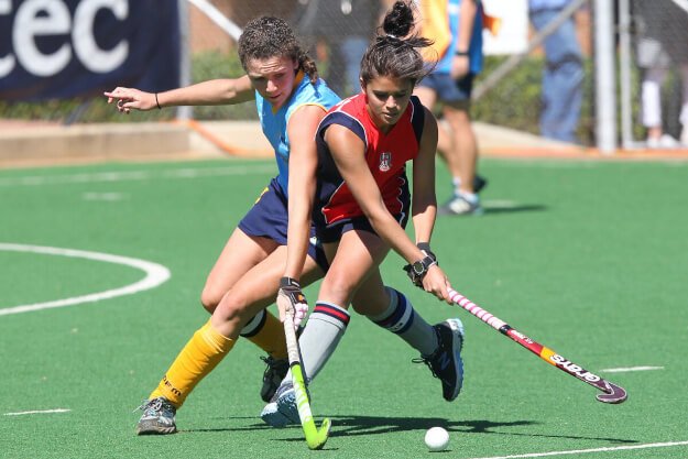 Two female athletes playing field hockey